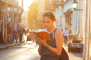 Junge Frau liest ein Buch in der Altstadt von Cartagena de Indias, Kolumbien - obrazy, fototapety, plakaty