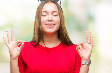 Young beautiful caucasian woman wearing sunglasses over isolated background relax and smiling with eyes closed doing meditation gesture with fingers. Yoga concept.