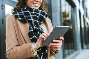 Woman outdoors walking by street using tablet computer.