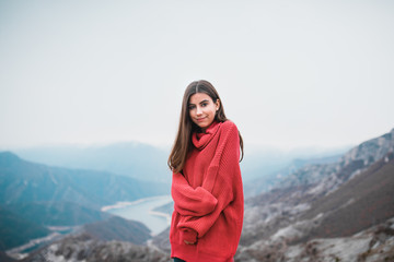 Beautiful Young Girl in a cosy red sweater on Mountain top