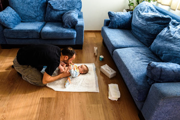 A father involved in taking care of his children by changing his daughter's dirty diaper. Concept...