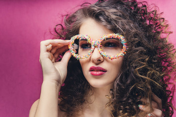 Beautiful girl with colourful manicure in confectionery dressing glasses