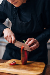 Chef slicing red pepper on a wooden board