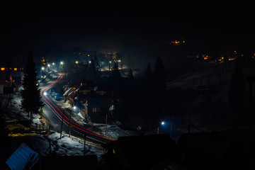 Fototapeta na wymiar Magnificent night landscape of the Ukrainian village in bright light and blurred automobile lights