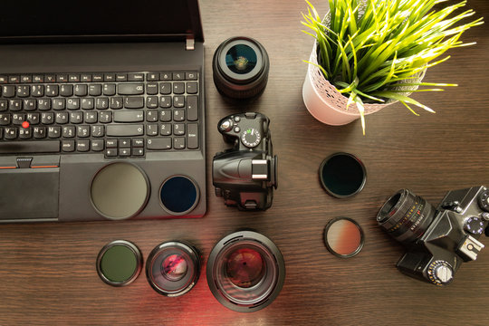 Abstract concept of modern photographer workplace: dark desk with photography gear, camera, lenses and acessories.