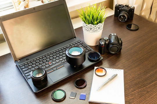 Abstract concept of modern photographer workplace: dark desk with photography gear, camera, lenses and acessories.