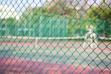 metal net with blur photo of tennis court in public park.