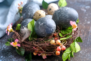 Blue easter egg in nest with flowers on dark vintage background