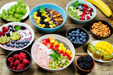 Smoothie breakfast bowls with berries, seeds and nuts on a wood background