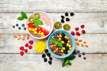 Smoothie breakfast bowls with berries, seeds and nuts on a wood background