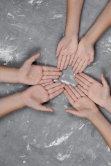 children's hands together in a circle on gray background, top view.