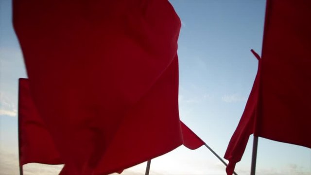 Red flags is waving against blue sky.