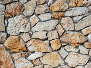 Wall of raw natural stone shades of brown.reinforced with cement