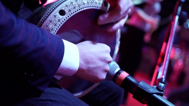 Closeup of hands playing roll on doumbek drumming fast rhythm with arabic background.
