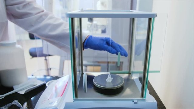 Hands of a microbiologist in gloves put a test tube