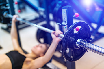Sexy athletic sport girl with perfect fitness body doing workout hard training with bar on incline bench in the gym