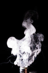 Splash glicerine on vape spiral. Two colour green and red clouds of fog with visible tracers. Vape culture and no smoking.