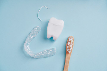 Ecological bamboo toothbrush, mouth guard and dental floss on blue