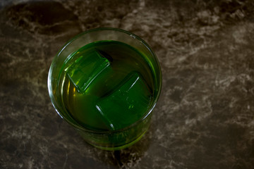 glass of whiskey with green ice