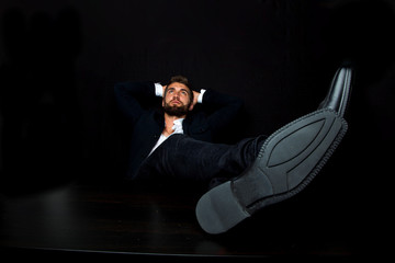 Portrait eines attraktiven bärtigen Geschäftsmannes mit Zigarre und die Beine auf dem Tisch....