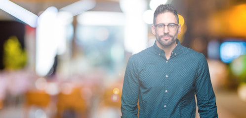 Young handsome business man wearing glasses over isolated background Relaxed with serious expression on face. Simple and natural looking at the camera.