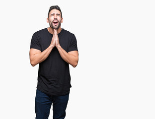 Fototapeta premium Young handsome man over isolated background begging and praying with hands together with hope expression on face very emotional and worried. Asking for forgiveness. Religion concept.