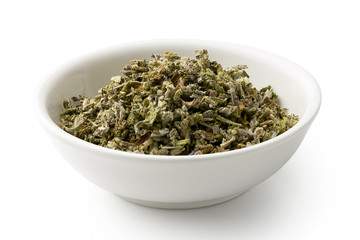 Dried rubbed sage in a white ceramic bowl isolated on white.