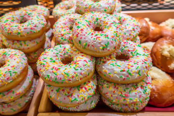 freshly baked glazed donuts with sprinkle in supermarket, food concept