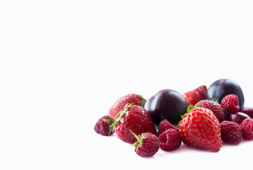 Ripe raspberries, strawberries, red berries and plums. Background of mix fruits with copy space for text. Mix berries on white background. Various fresh summer.