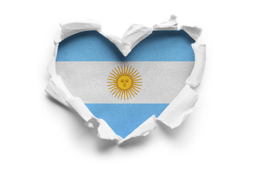 Heart shaped hole torn through paper, showing satin texture of flag of Argentina. Isolated on white...