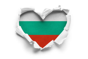 Heart shaped hole torn through paper, showing satin texture of flag of Bulgaria. Isolated on white...