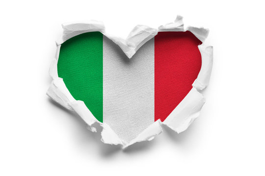 Heart shaped hole torn through paper, showing satin texture of flag of Italy. Isolated on white background