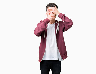 Young handsome man over isolated background Covering eyes and mouth with hands, surprised and shocked. Hiding emotion