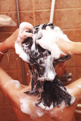 Naklejka premium A Girls washing her hair in shower with Champoo