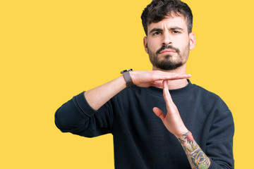 Young handsome man over isolated background Doing time out gesture with hands, frustrated and...