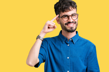 Young handsome man wearing glasses over isolated background Smiling pointing to head with one finger, great idea or thought, good memory