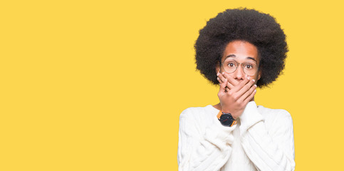 Fototapeta na wymiar Young african american man with afro hair wearing glasses shocked covering mouth with hands for mistake. Secret concept.
