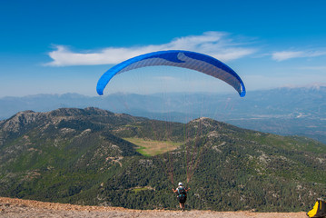 The paraglider starts flying from the mountain. Turkey Oludeniz.