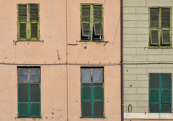 Fototapeta premium Close-up of a coloured building faaçde with rows of windows and green shutters, Genoa, Liguria, Italy