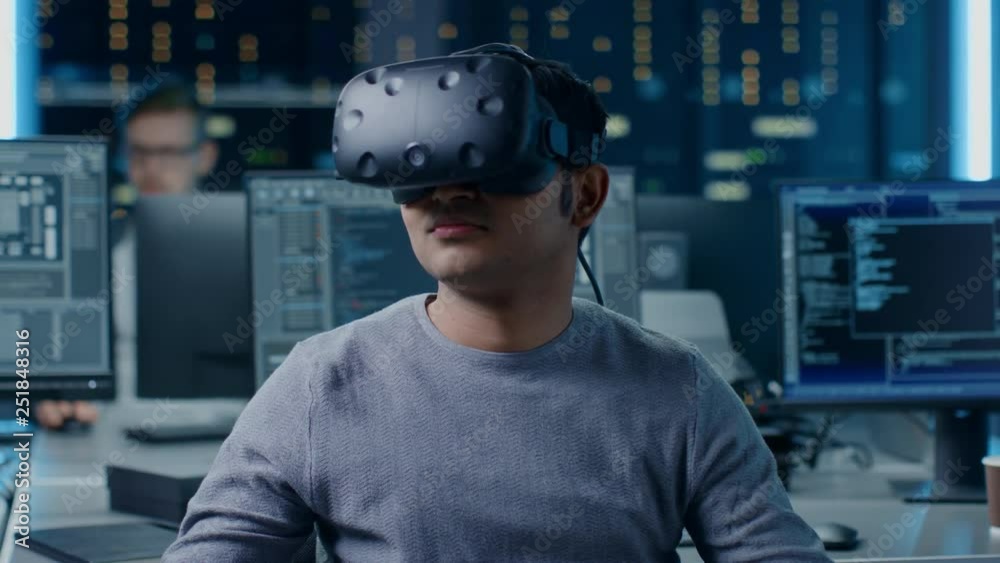 Poster Software Delevoper Wearing Virtual Reality Headset Gesturing with His Head, Developing and Programming VR Game or Application. In Background Technology Developing Studio with Computers and Monitors