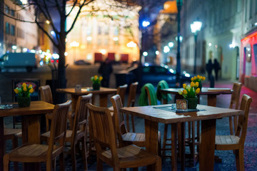 Outdoor restaurant with wooden tables on the European square. Empty outdoor Cafe. Blurred background.