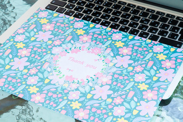 A thank you card sitting on a computer keyboard, online thank you.