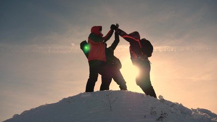 team work and victory. Tourists come to top of snowy hill and rejoice at victory against backdrop...