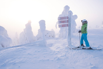 Girl skier looks at the direction indicator. Choice of direction in winter tourism and travel.