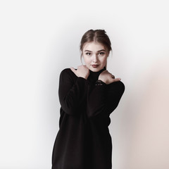 portrait of a young girl in a black dress on a light background in the studio