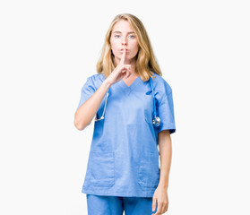 Beautiful young doctor woman wearing medical uniform over isolated background asking to be quiet...