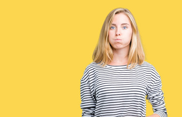 Beautiful young woman wearing stripes sweater over isolated background puffing cheeks with funny face. Mouth inflated with air, crazy expression.