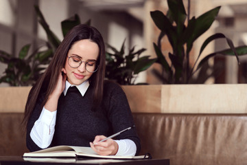 Young girl wearing glasses writting something in her notebook