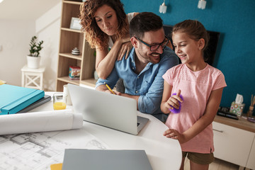 Middle age businessman working at home.Wife and daughter  stands beside and support him.
