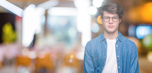 Fototapeta na wymiar Young handsome man wearing glasses over isolated background Relaxed with serious expression on face. Simple and natural looking at the camera.